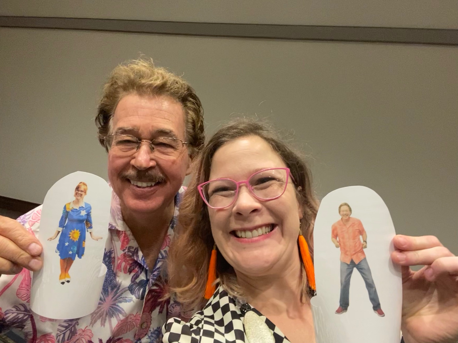 Sally and children's music legend Jack Hartmann smiling together and holding paper puppet cutouts of each other