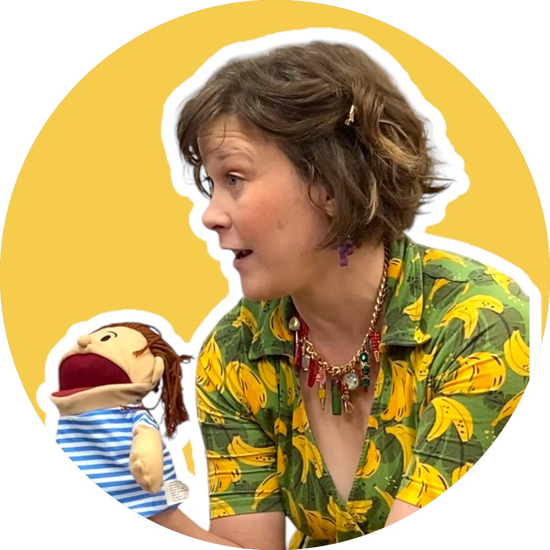 Sally Sparks smiling with Billy Bully puppet in a colorful classroom